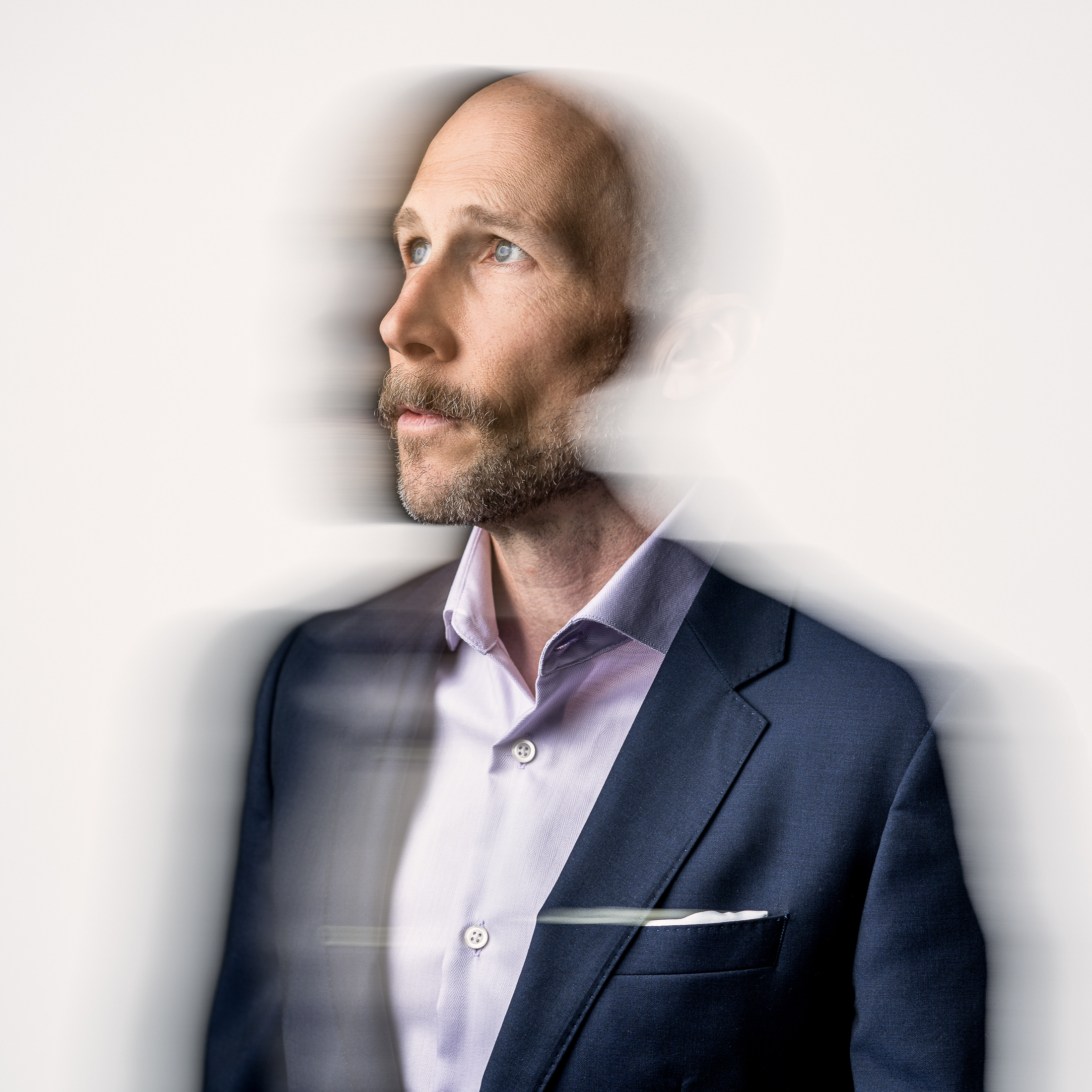 studio portrait, white background, bald man in suit with pocket square, lots of motion blur