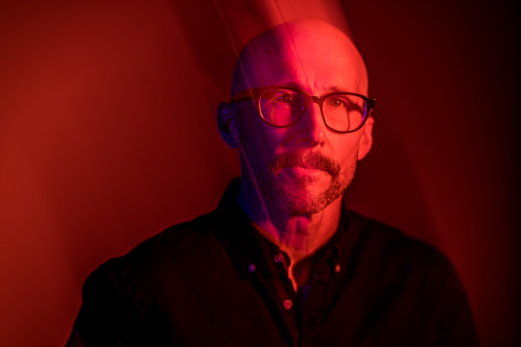 studio portrait of bald man with beard, red color, motion blur